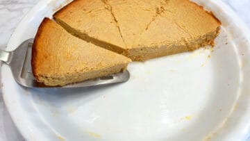 Lifting a slice of keto pumpkin cheesecake from the pan.