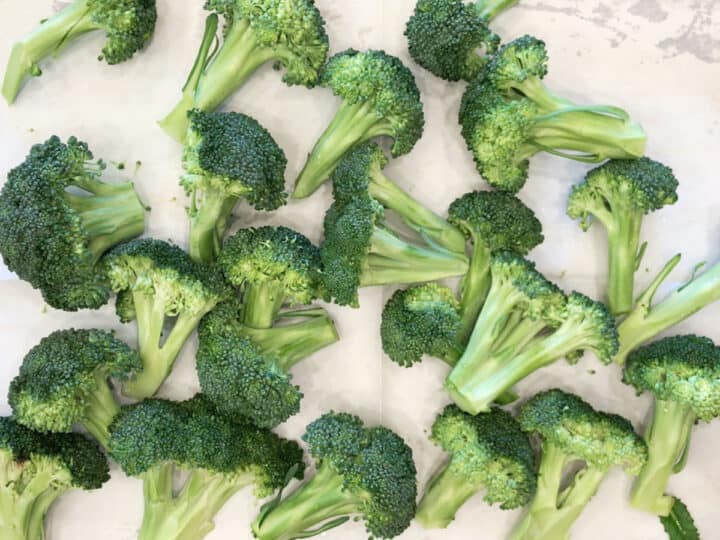 Broccoli florets on a parchment-lined baking sheet.