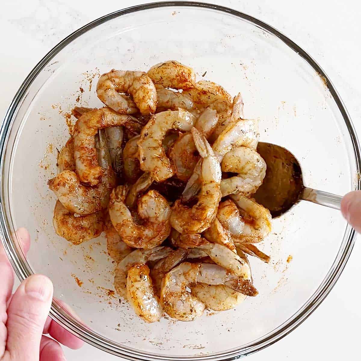 Mixing the shrimp with oil and spices.
