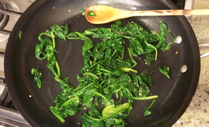 Spinach is wilted in the skillet.