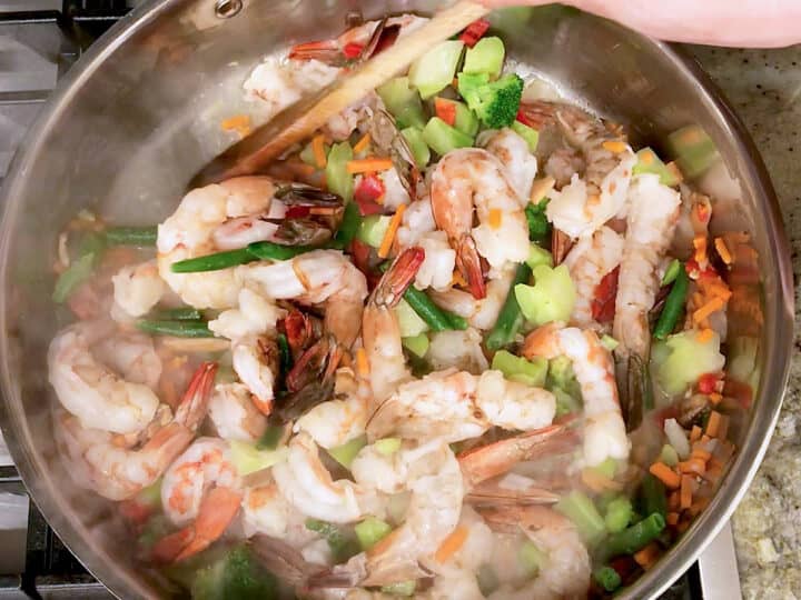 Cooking shrimp and vegetables in a skillet.
