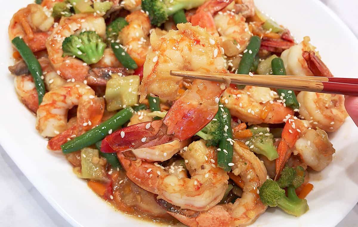 Shrimp stir-fry is served with chopsticks. 