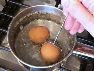 Lowering the eggs into the boiling water.