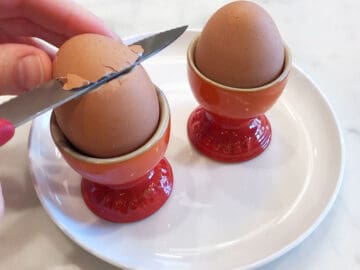 Opening a soft-boiled egg with a knife.