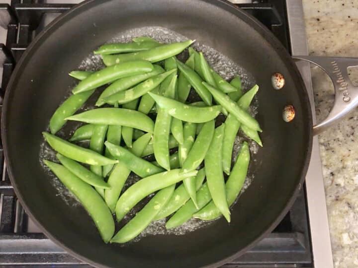 Adding the snap peas to the skillet.