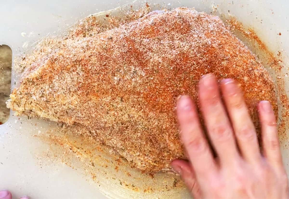Sprinkling a turkey breast with spices. 