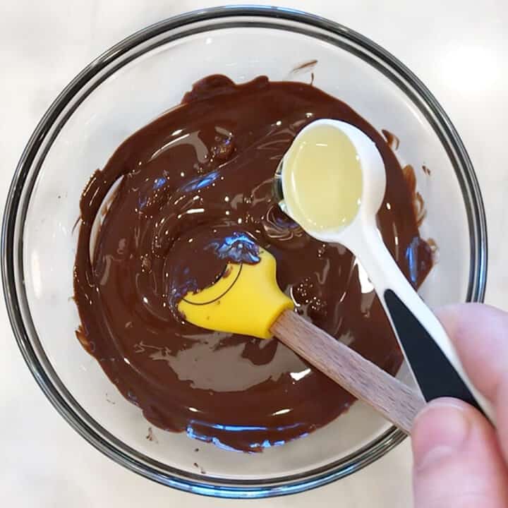 Adding oil to melted chocolate.