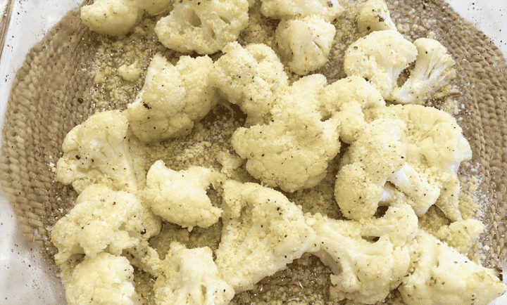 Sprinkling the partially baked cauliflower with parmesan.