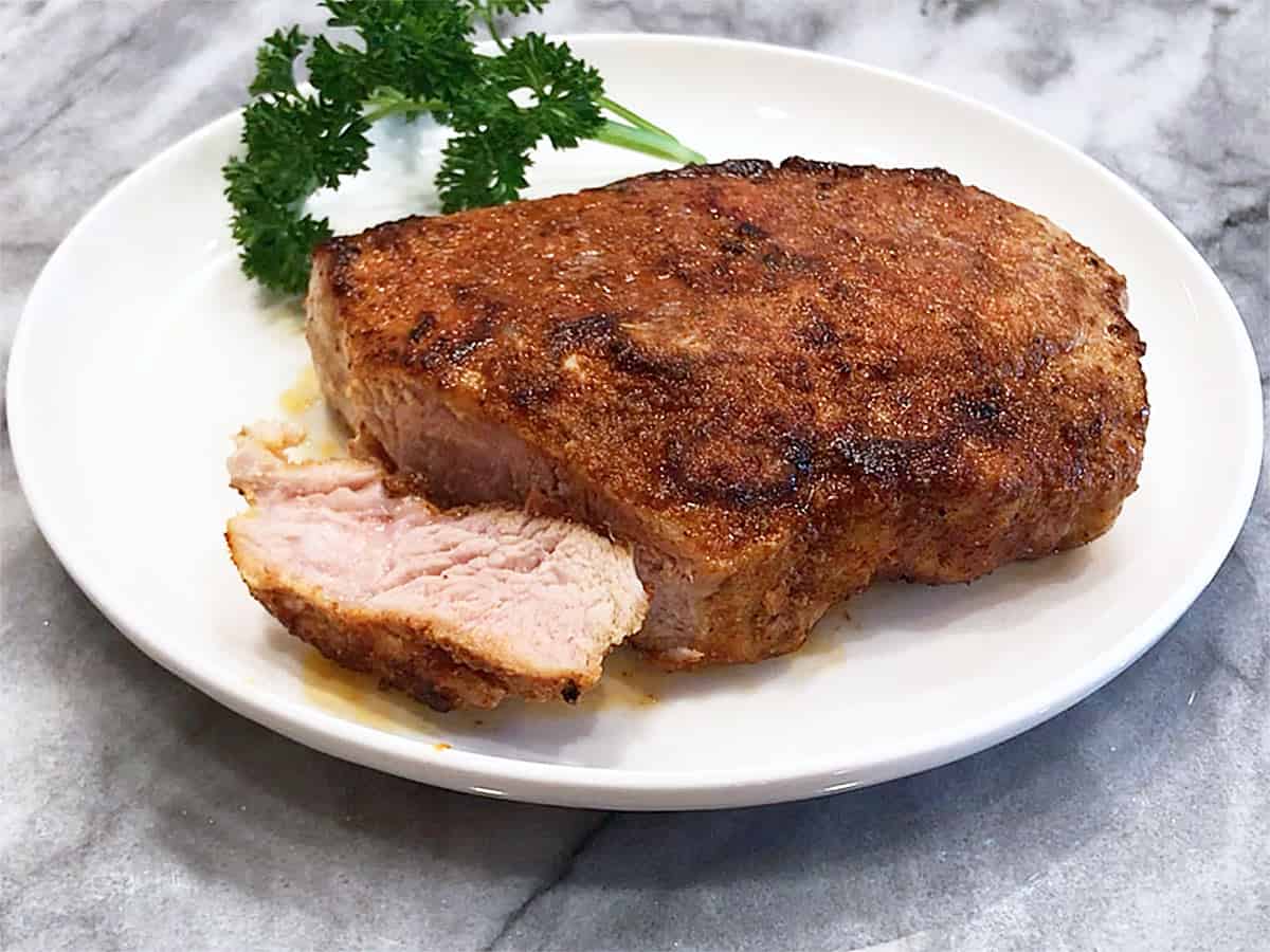 A baked pork chop, cut to show that the inside is slightly pink. 