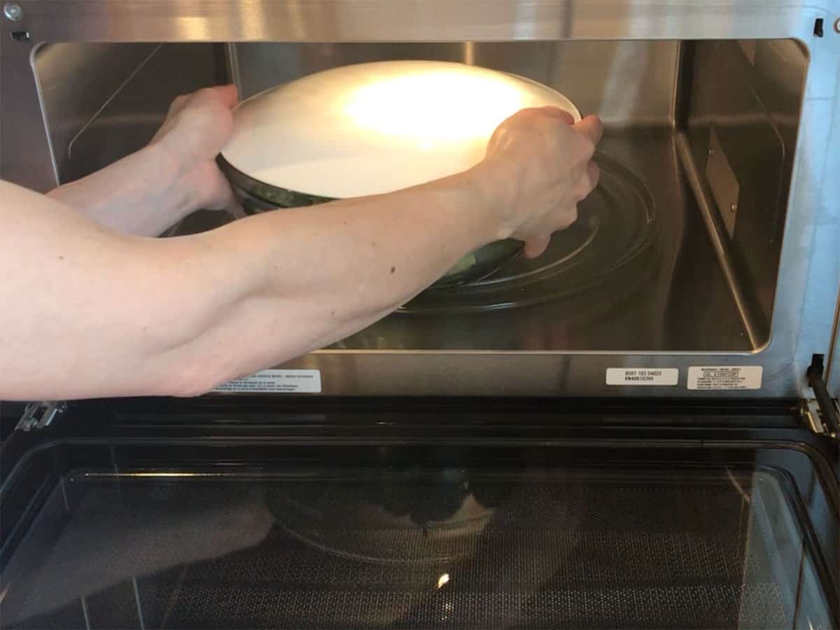 Placing a bowl with broccoli in the microwave.