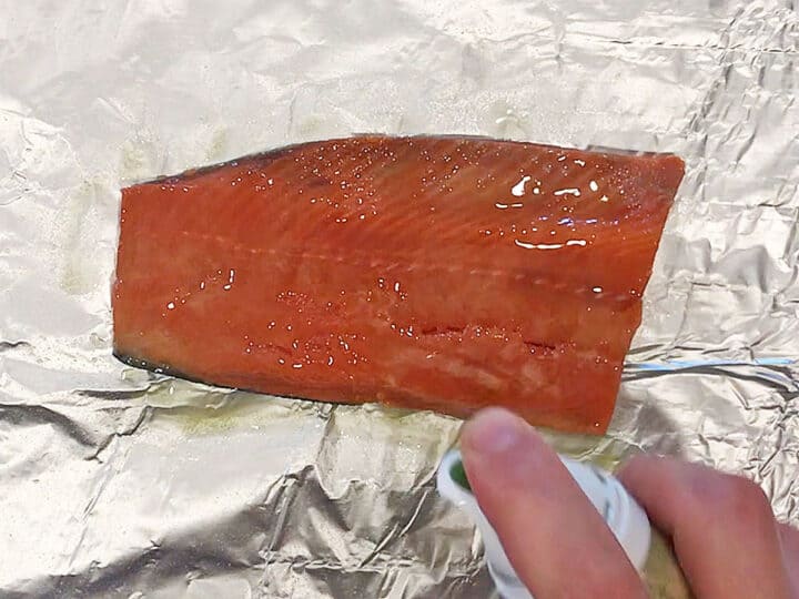 Spraying a salmon fillet with olive oil.