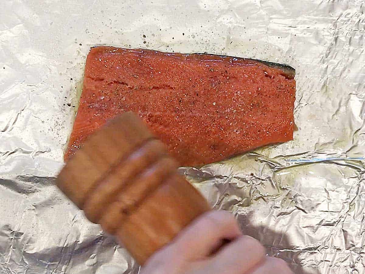 Seasoning a salmon fillet with freshly ground black pepper. 