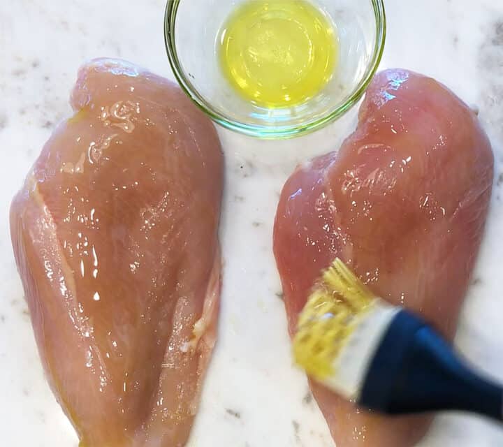 Brushing chicken breasts with oil.