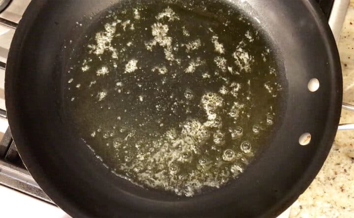 Heating olive oil in a skillet.