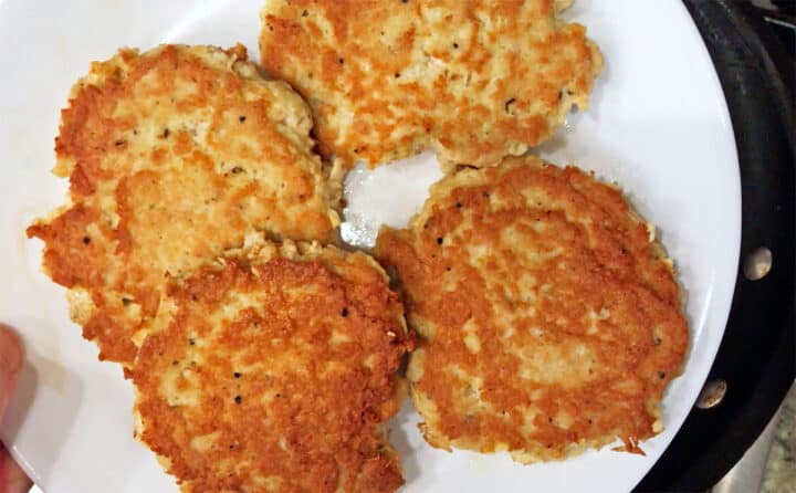 Four cooked chicken patties on a plate.