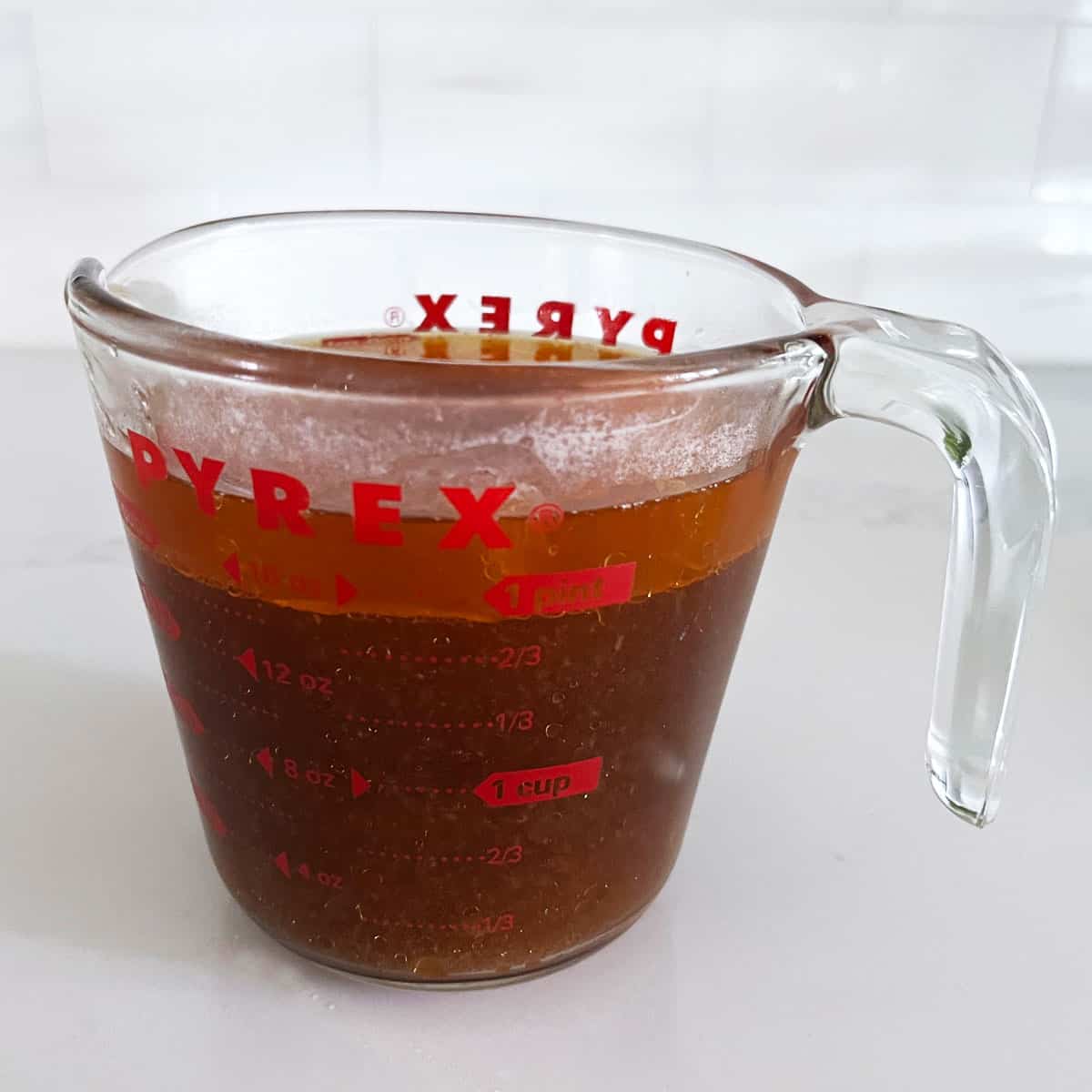 Cooking juices in a measuring cup with a fat layer on top.