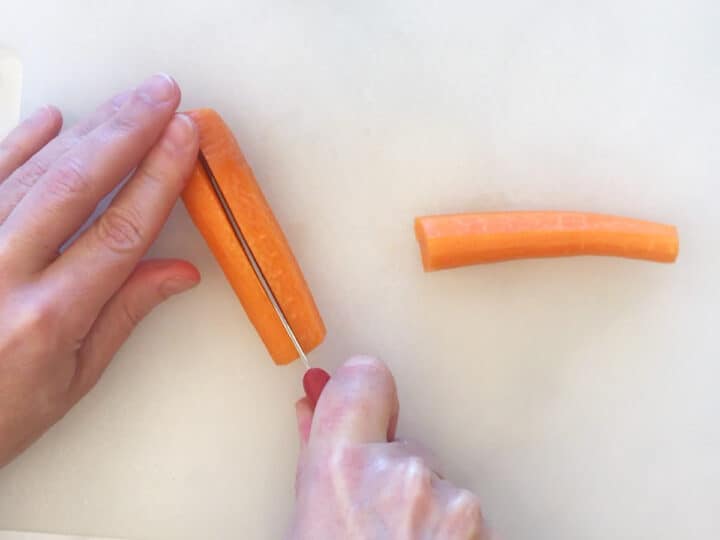 Cutting the thick half of the carrot lengthwise.