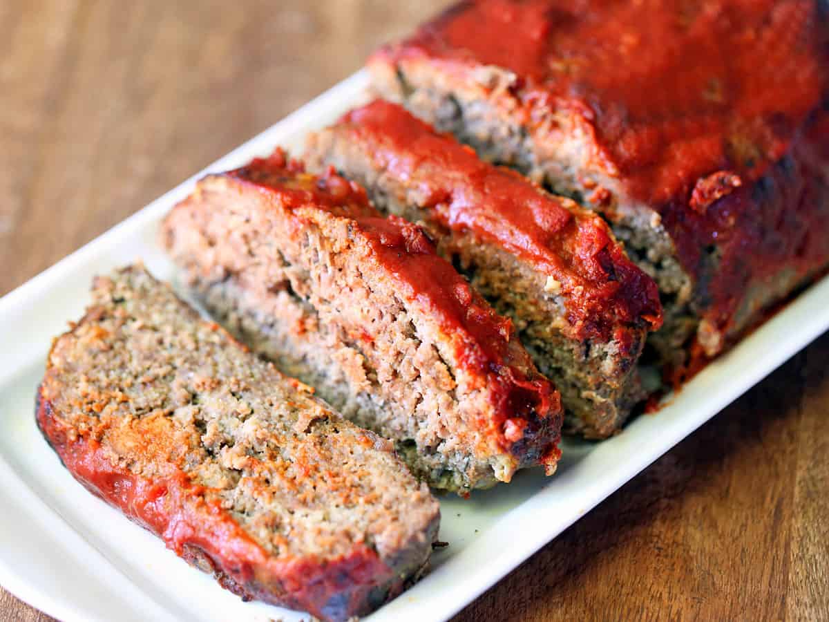 A sliced keto meatloaf on a white tray.