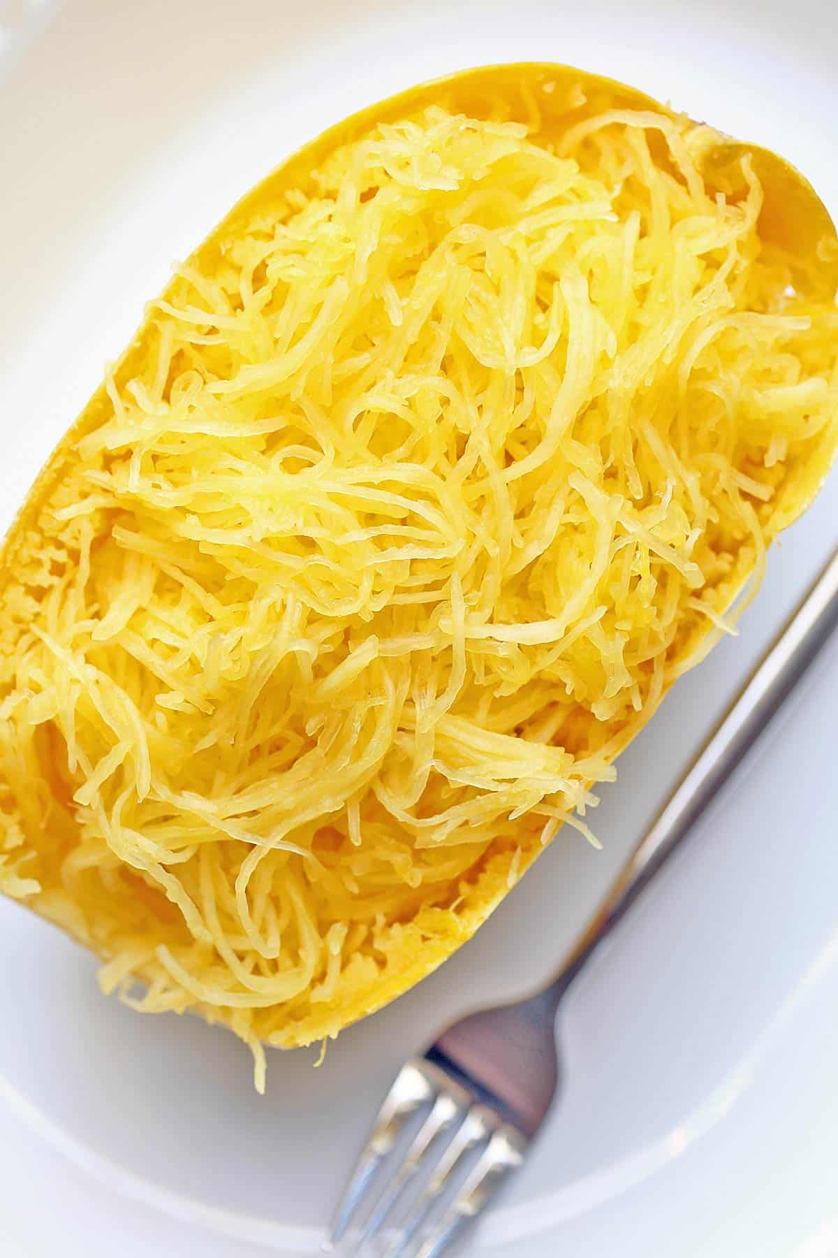Microwave spaghetti squash served on a white plate with a fork. 