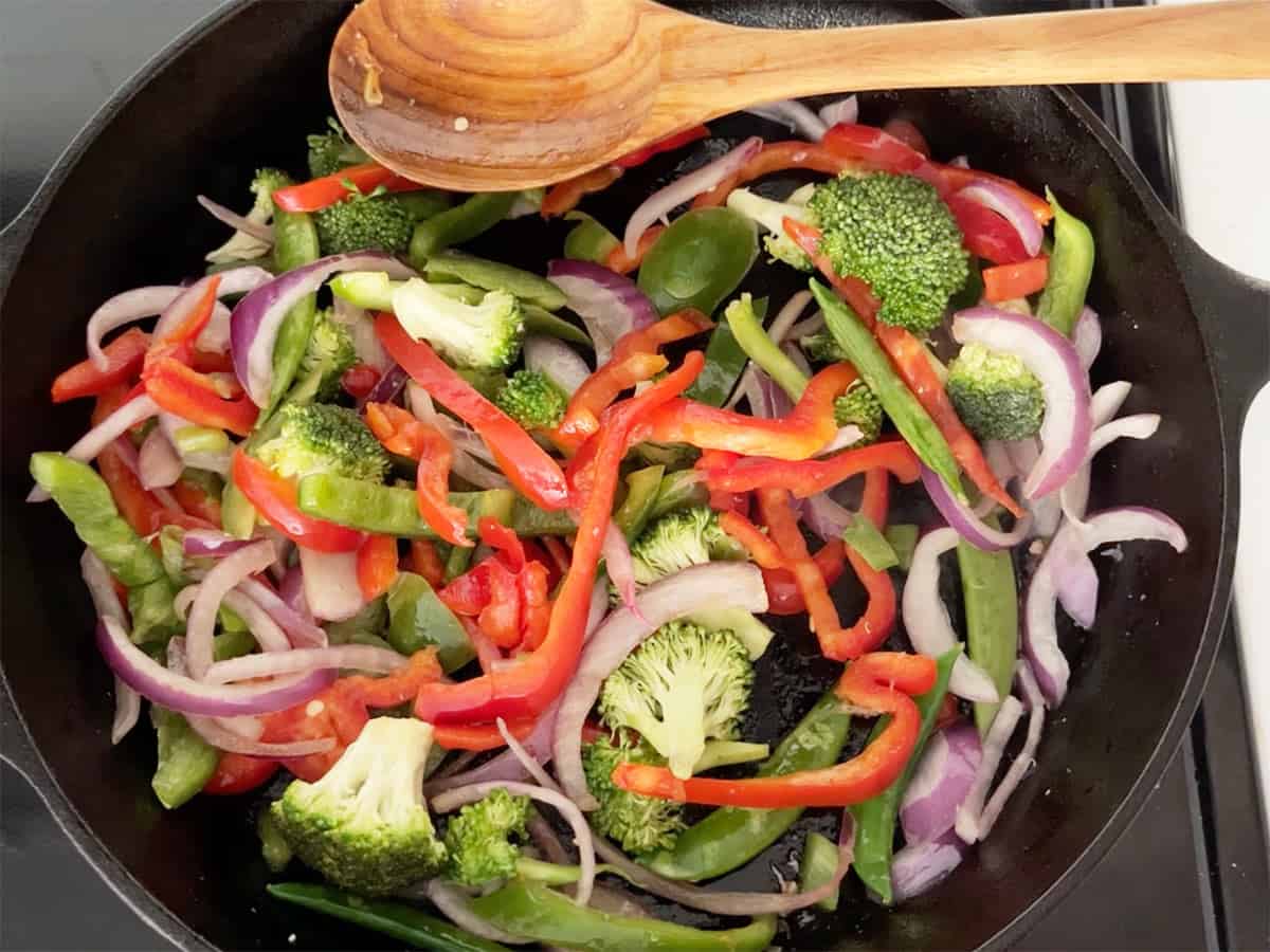 Cooking veggies for pork stir-fry in a skillet. 