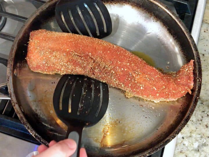 Placing a pork tenderloin in a skillet.