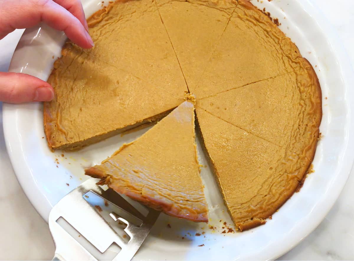 Lifting a slice of pie from the pan with a cake server. 