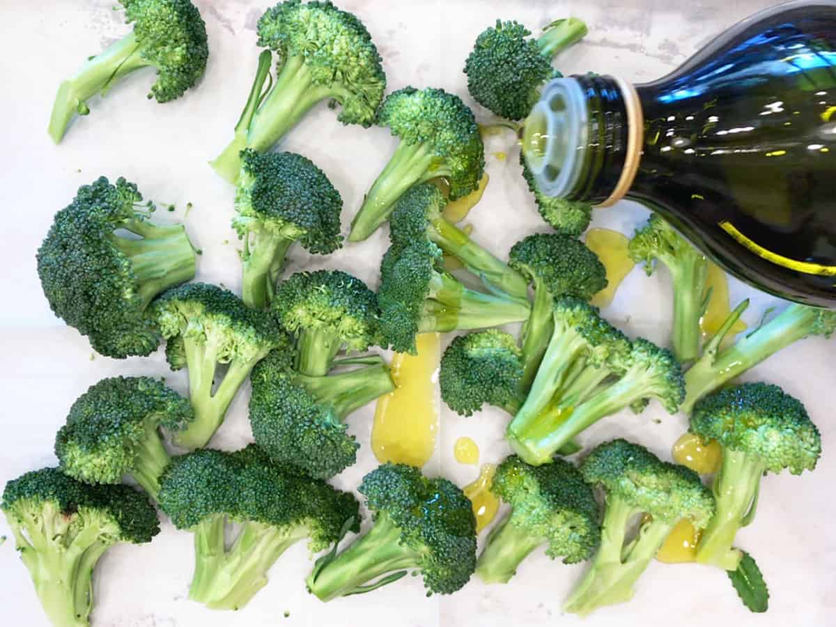 Drizzling broccoli florets in the pan with olive oil.