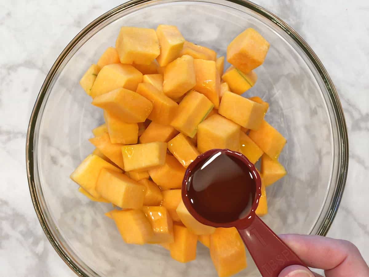 Add olive oil to butternut squash cubes in the bowl.