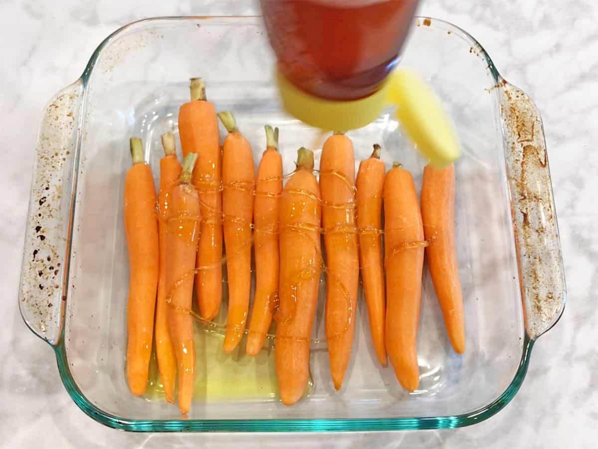 Add honey to the carrots in the baking dish.