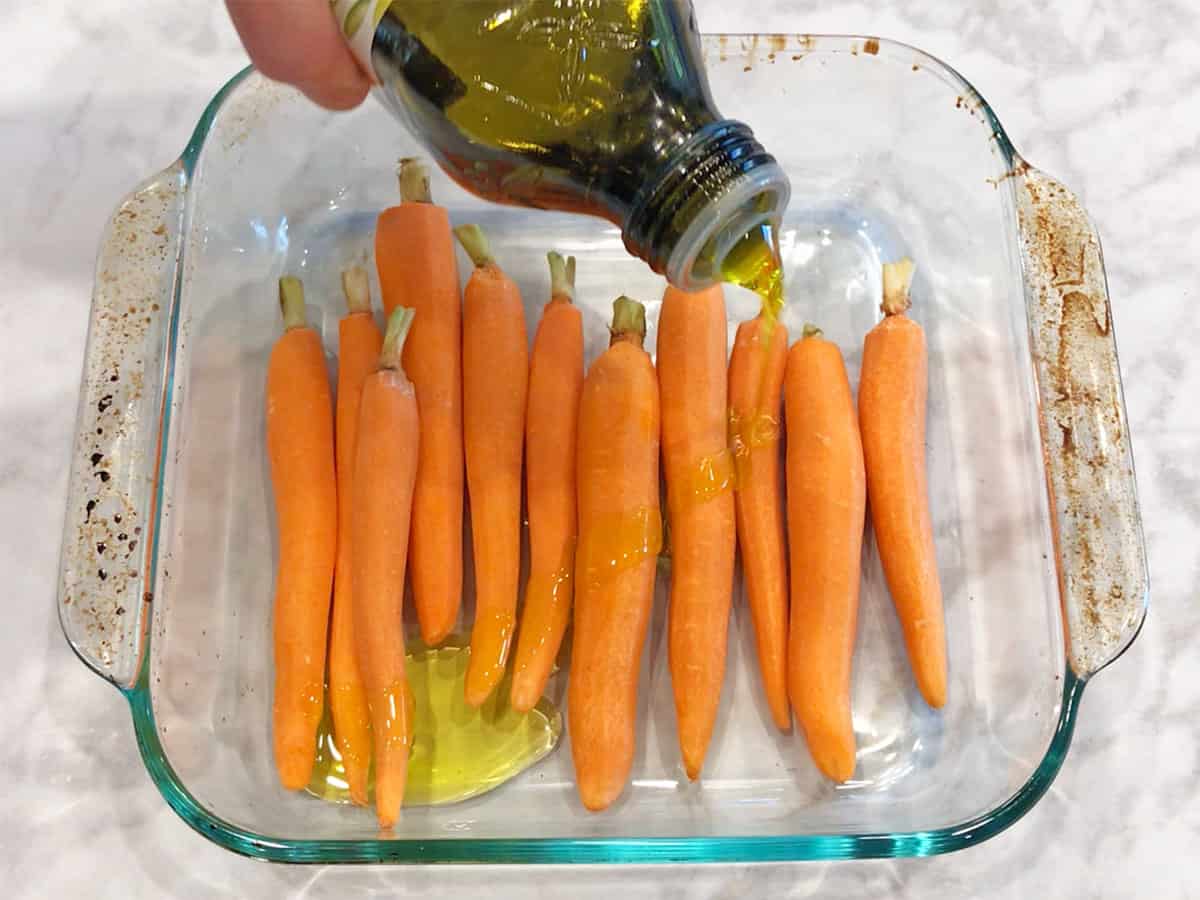 Add olive oil to the carrots in the baking dish.