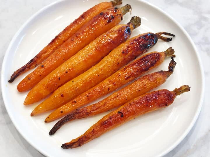 Roasted carrots are served on a white plate.