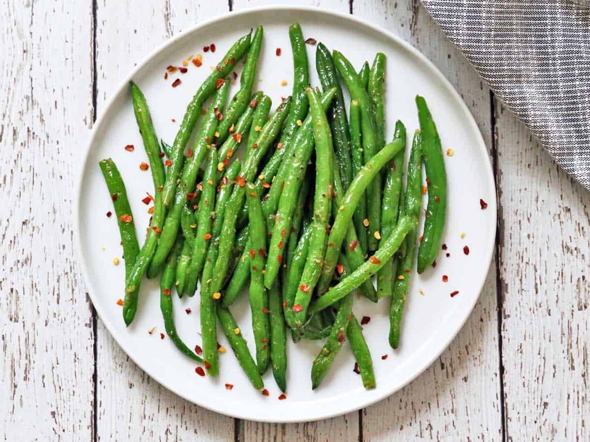 Sauteed green beans on a white plate.