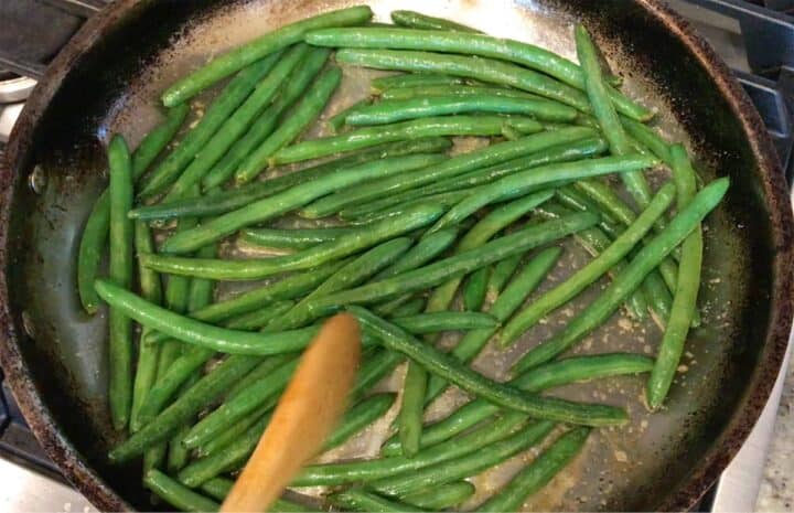 Sauteing the green beans in a large skillet.