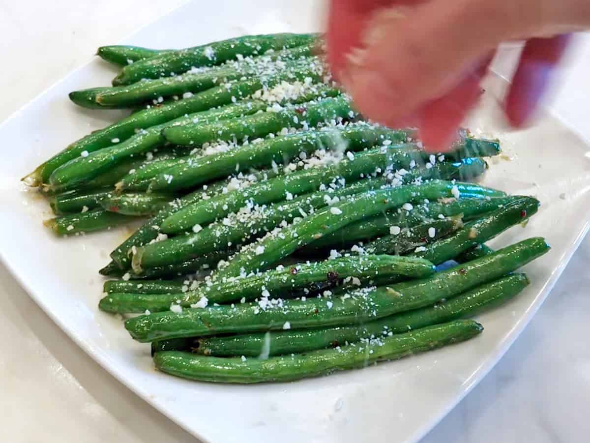 Topping sauteed green beans with parmesan.