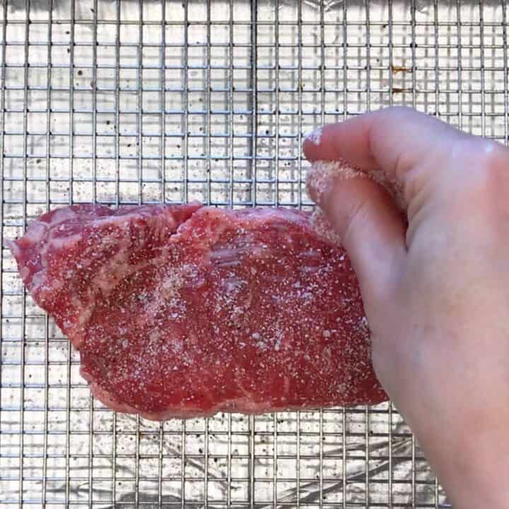 Seasoning steak with salt.
