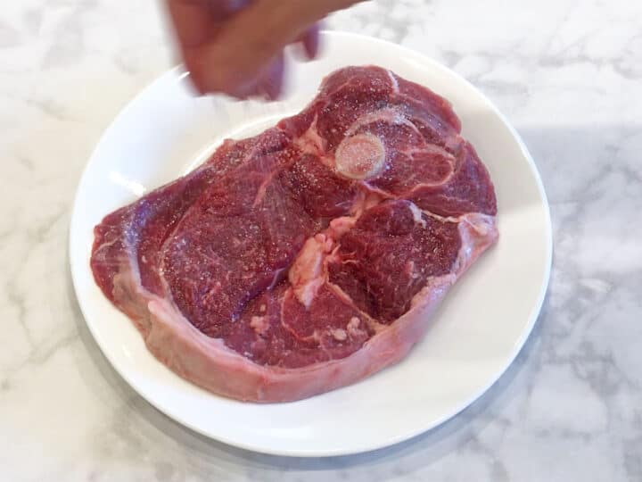 Seasoning a lamb steak.