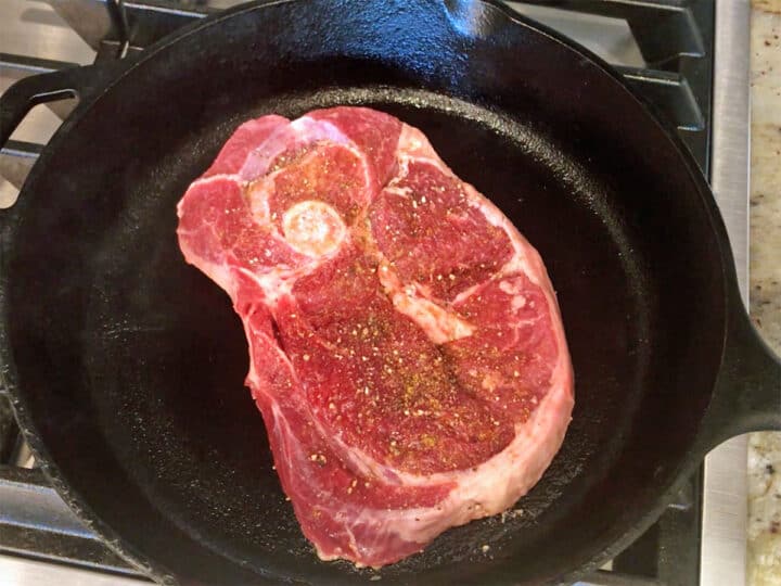 Lamb steak in a cast-iron skillet.