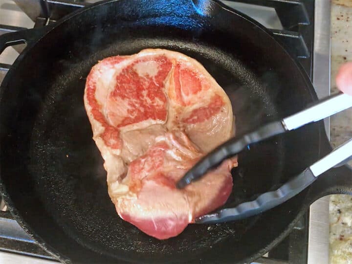 Flipping the steak in the skillet.