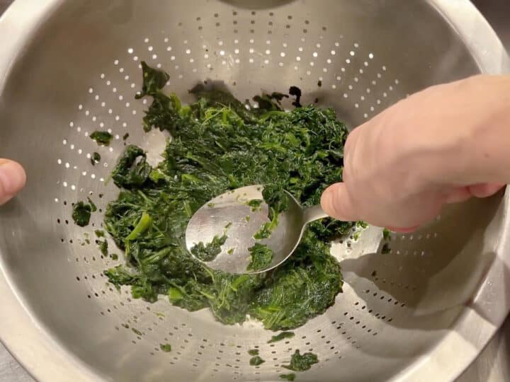 Draining spinach in a colander.