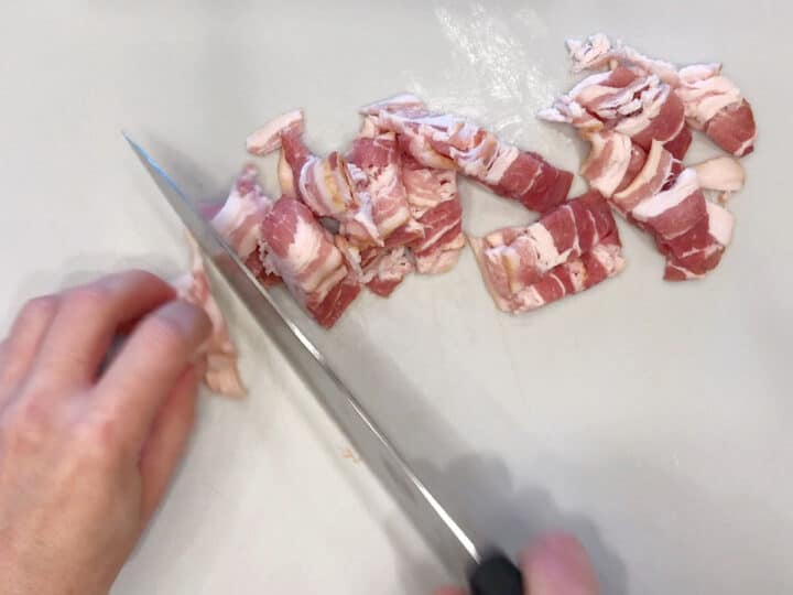 Cutting bacon into pieces.