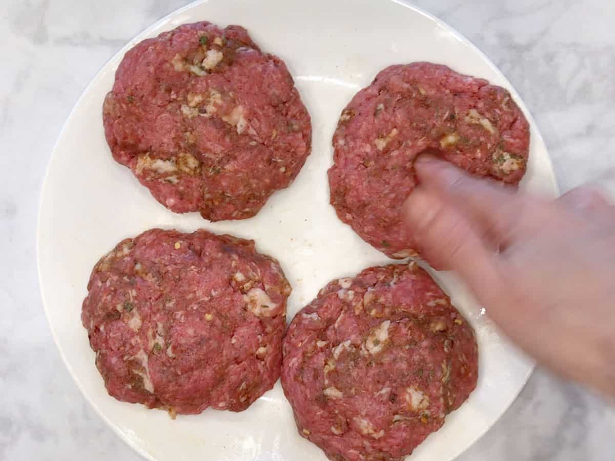 Making a dimple in the center of the burgers.