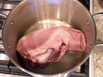 Raw beef tongue in a stockpot.