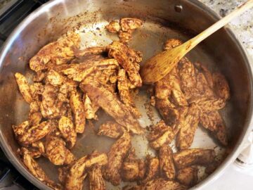 Cooking chicken with spices in a skillet.