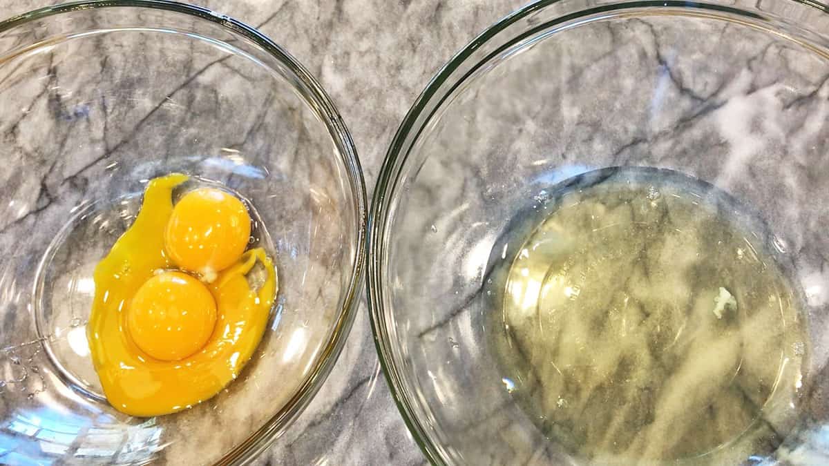 A bowl with egg whites next to a bowl with egg yolks.
