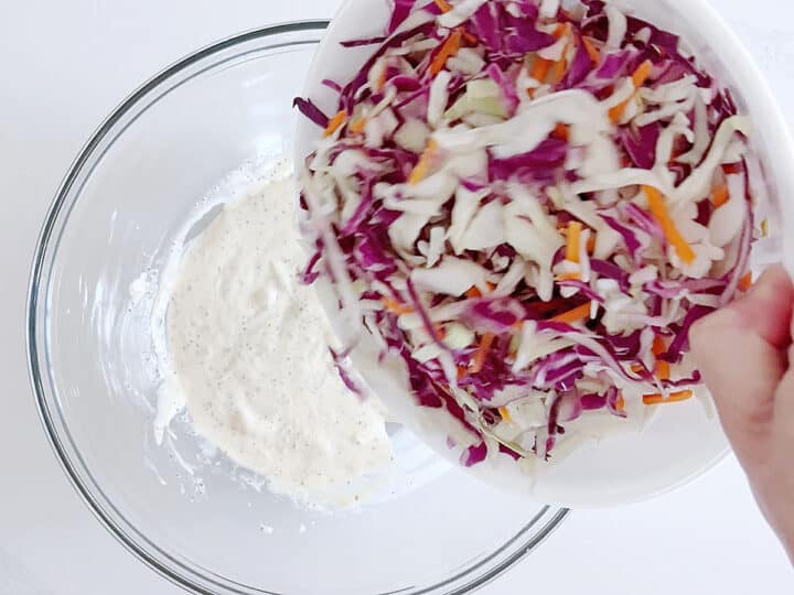 Adding the shredded cabbage to the dressing.