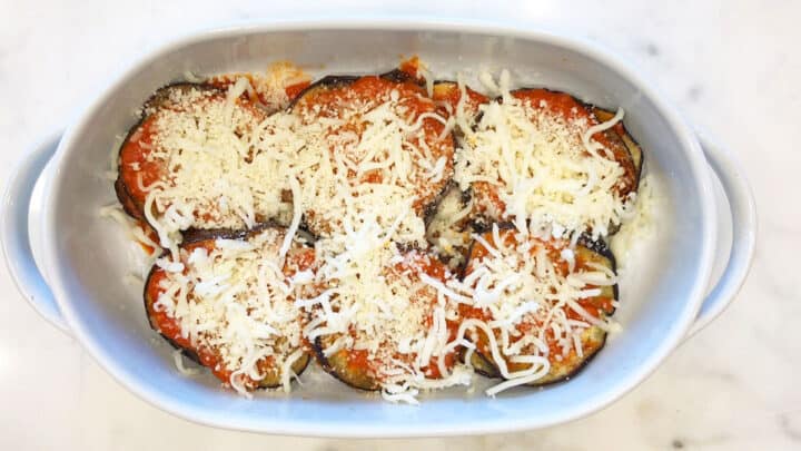 Another layer of eggplant slices, marinara, and cheese in a casserole dish.