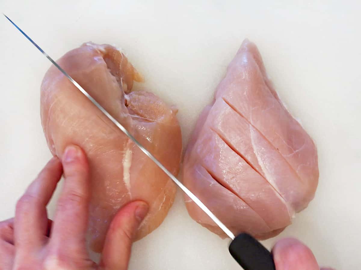 Cutting shallow slits across the top of each chicken breast.