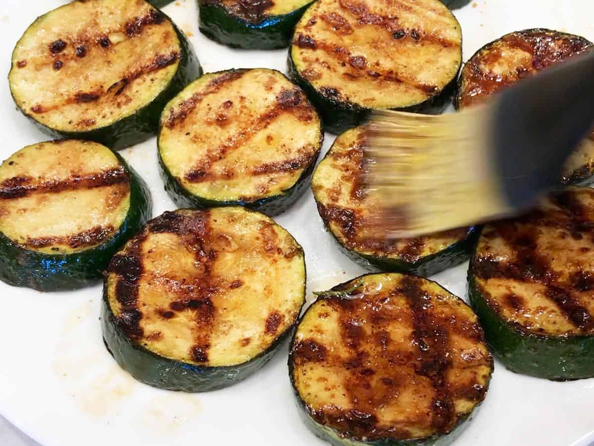 Brushing the grilled zucchini with the remaining marinade.
