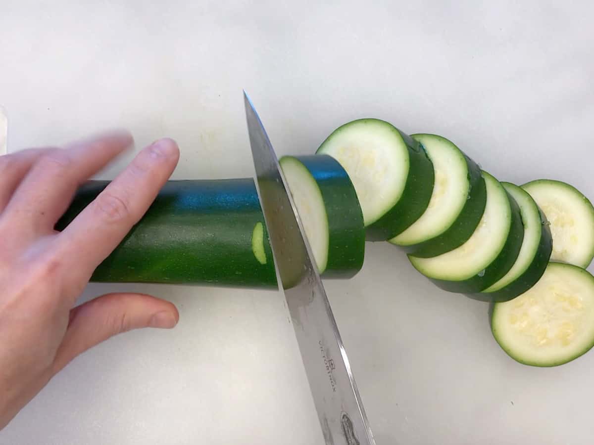 Slicing the zucchini with a knife.