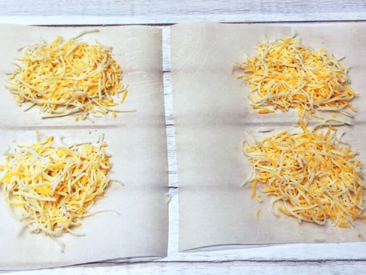 Four mounds of shredded cheese on parchment paper.